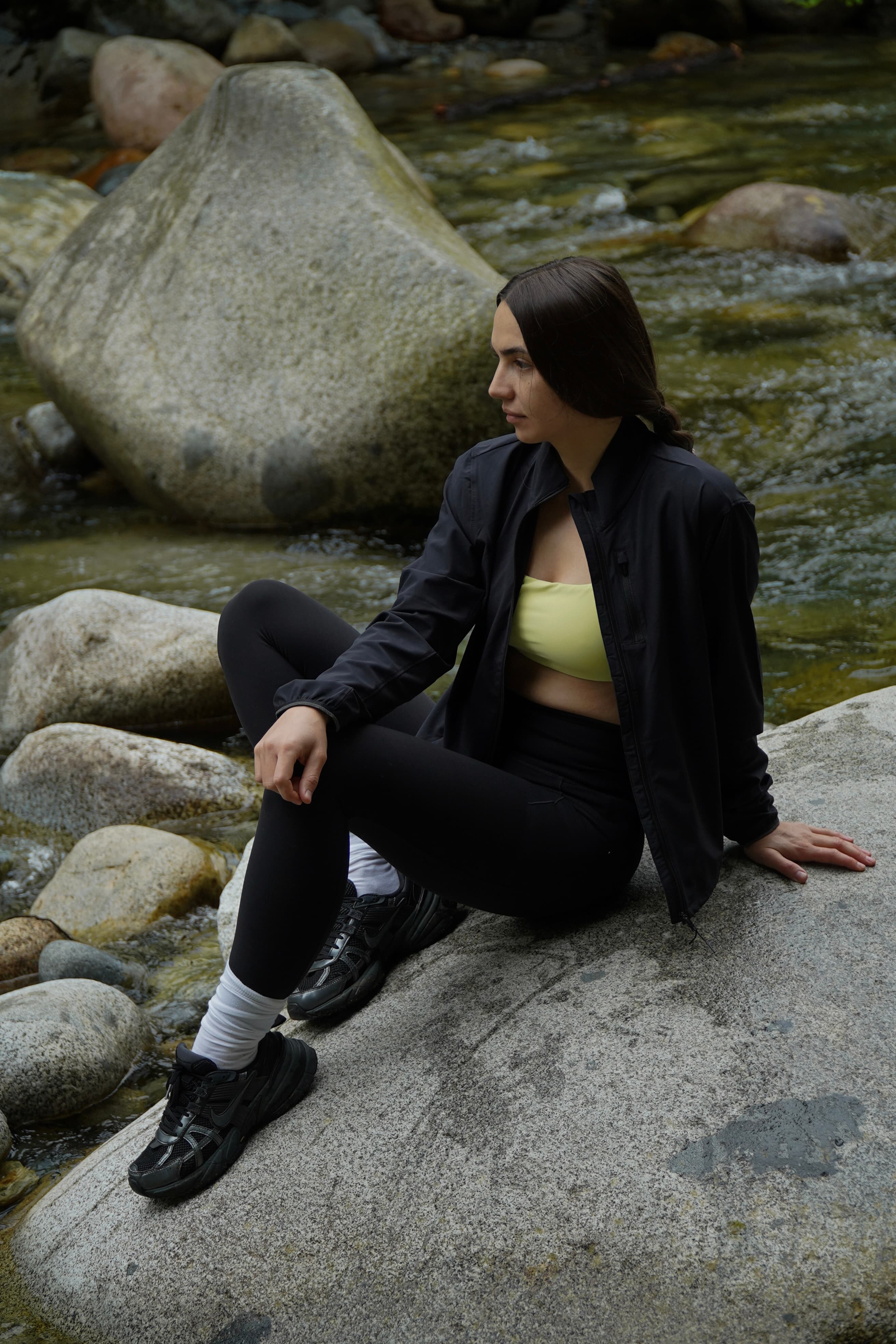 Editorial — sitting on river boulder in Athleta